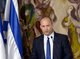 El ministro israelí Naftali Bennett hablando junto a dos banderas de Israel. De fondo, murales de Chagall en el parlamento israelí