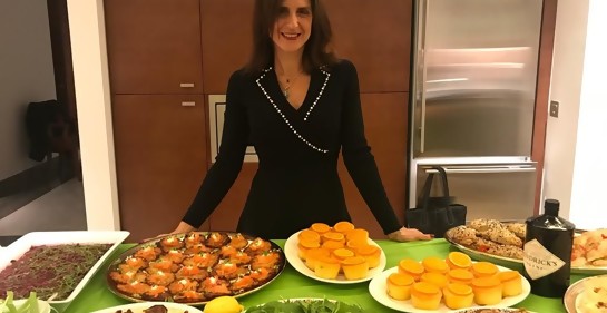 Elli Kriel de pie junto a una mesa con diferentes fuentes multicolores de comida