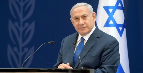 Netanyahu, de traje azul, detrás suyo una bandera de Israel