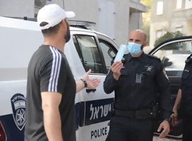 Un policía entregando una máscara a un ciudadano