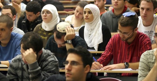 Una clase llena de estudiantes en la universidad, algunos judíos seculares, otros con kipá de judíos religiosos, y en el medio dos jóvenes árabes musulmanascon hijab blanco