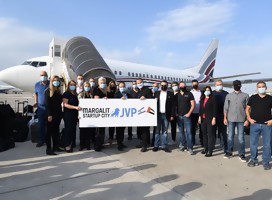 Un grupo de empresarios junto a un avión, con un cartel que dice Margalit Start up city