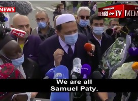 ImamChalgoumi, con tapabocas, hablando a la prensa, rodeado de micrófonos y mucha gente