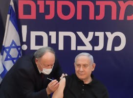 Netanyahu vacunándose. De fondo un cartel  vacuándose se gana