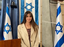 Una joven mirando a la cámara, rodeada de banderas de Israel